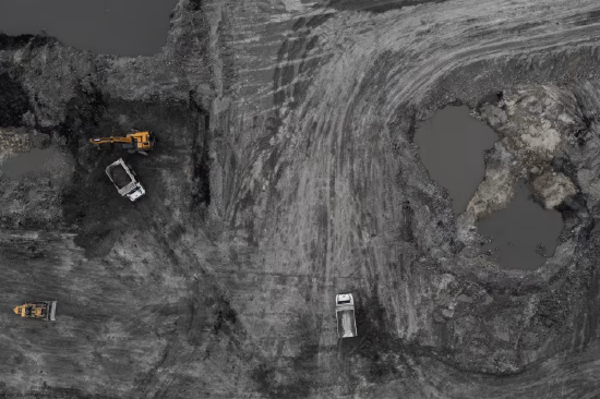 中国内蒙古一座露天煤矿，矿场内停放矿用卡车与挖掘机的航拍景象。